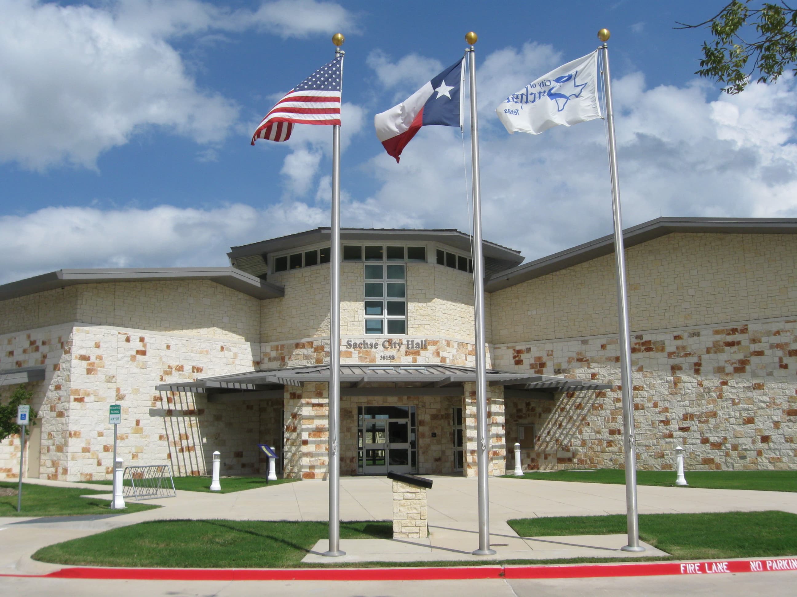 Sachse, Texas City Hall stone-clad civic building with U.S., Texas, and city flags flying out front